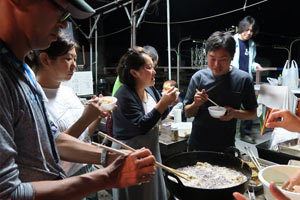 揚げる野沢さん、食べる3人